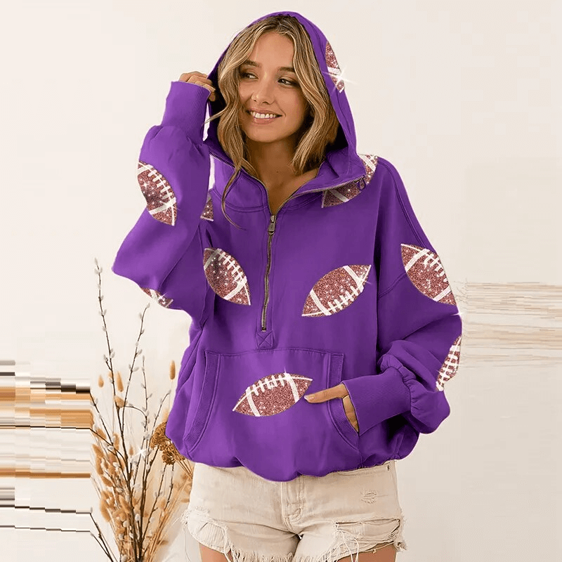 Woman wearing a sporty casual purple hoodie with football decals, front pockets, and hood, styled with denim shorts. SF1598